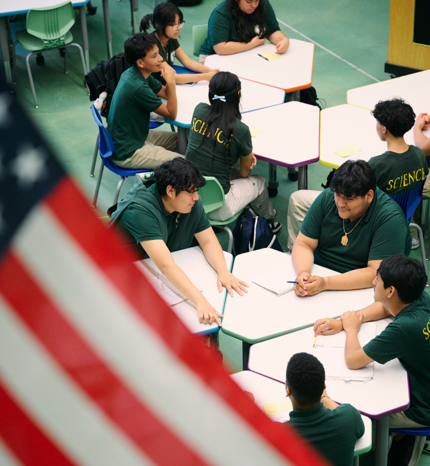 top view of students around tables with U.S. flag foregrounded